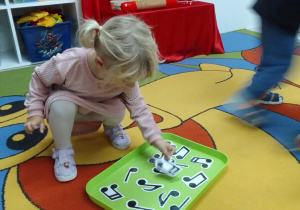 Emilia kładzie na tacy nutę muzyczną odnalezioną w sali.