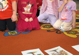 Grupa dzieci ogląda obrazki na dywanie