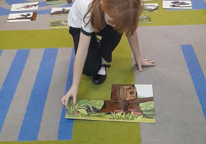 Na dywanie leżą elementy układanki edukacyjnej "Drzewo". Emma po wysłuchaniu krótkiej rymowanki układa pierwsze elementy obrazka.