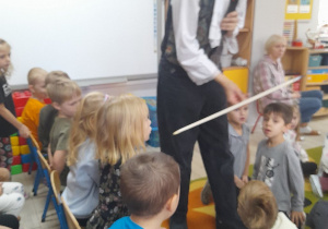 Pan prowadzący audycję pokazuje dzieciom smyczek.