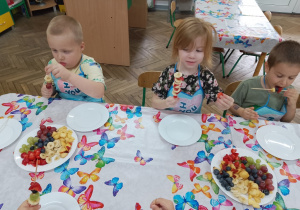 7.Karol i Jagoda nawlekają ulubione owoce na patyczek, a Tymek już zajada przygotowany szaszłyk.
