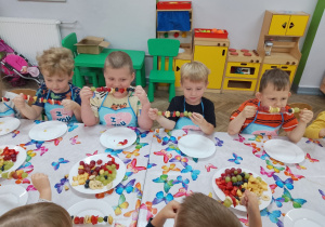 10.Grupka chłopców zjada owocowe szaszłyki.