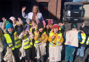 Dzieci pozują do zdjęcia z Panią właścicielką. Przedszkolaki z radością machają rękami.