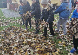 8.Dzieci z grupy Biedronek w ogrodzie przedszkolnym układają mrówkę z jesiennych liści