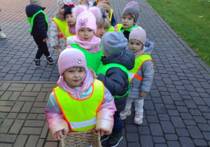 Maluchy wychodzą z przedszkola, Laura trzyma w rękach koszyczek na jesienne skarby.