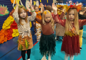 Dziewczynki tańczą przy muzyce z rękami podniesionymi do góry.