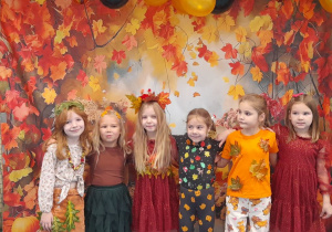 Sześć dziewczynek pozuje do wspólnego zdjęcia. W tle baner z motywem jesiennym i balonowa girlanda.