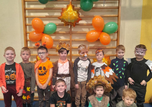 Grupka chłopców w jesiennych strojach pozuje do wspólnego zdjęcia. W tle drabinki ozdobione balonami.