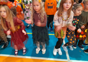 Grupka dzieci tańczy obok siebie przy muzyce.