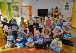 Dzieci z grupy "Motylków" pozują do zdjęcia z zawieszkami i kolorowankami edukacyjnymi.