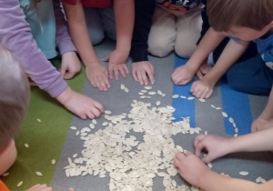 Dzieci na dywanie układają dynię z pestek.