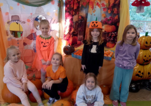 Grupka dziewczynek pozuje do zdjęcia na tle dekoracji.