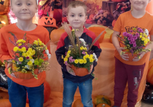 Hubert, Bartek i Antek trzymają wykonane dyniowe kompozycje.