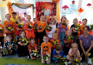 Zdjęcie grupowe na tle dekoracji z okazji Dnia Dyni z wykonanymi dyniowymi kompozycjami.