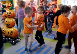 Dzieci tańczą w małych kółeczkach do piosenki o dyni.