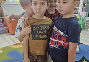 Grupa chłopców stoi w okręgu, przed dziećmi widać kostkę z wyrzuconymi pięcioma kropkami.