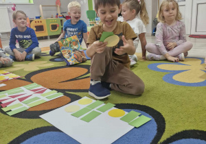 Wojtuś układa na dywanie wzór z figur geometrycznych.