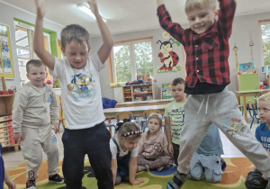 Franek i Olek skaczą robiąc pajacyki. Przed dziećmi wydać wyrzucone kostki liczbowe.