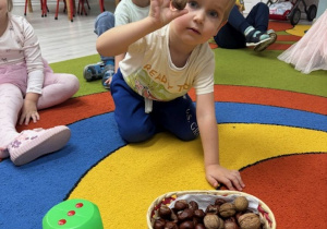 Chłopiec po rzucie kostką przelicza orzechy włoskie.