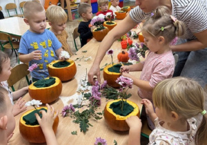 Dzieci przy pomocy Pani z firmy ,"Od serca robione" układają kompozycje kwiatowe