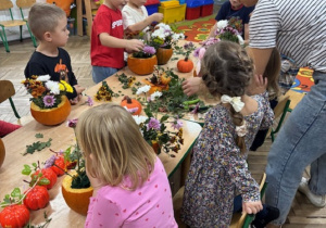 Dzieci przy pomocy Pani z firmy "Od serca robione" układają kompozycje kwiatowe