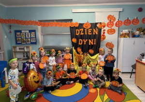 Dzieci pozują ze swoimi pracami plastycznymi na tle dekoracji.