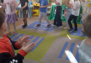 Dzieci idą w kole w kole i naśladują tekst piosenki "Witajcie w naszej bajce".