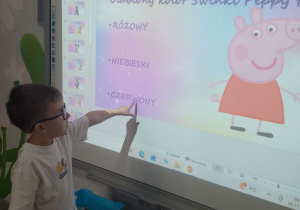 Chłopiec na tablicy interaktywnej wskazuje prawidłową odpowiedź quizu nt. bajek.