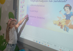 Tosia rozwiązuje quiz nt. bajek na tablicy interaktywnej.