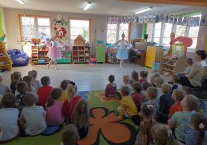 Dwie tancerki ubrane w sukienki - niebieską i różową tańczą przy muzyce naśladując księżniczki zaczarowane w ptaki.