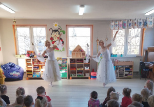 Dwie tancerki w białych sukniach prezentują kolejny taniec.