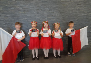 Pięcioro dzieci pozuje do zdjęcia z dyplomami.