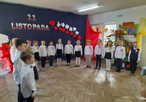 Dzieci z grupy "Słoneczka" śpiewają hymn narodowy. W tle dekoracja z okazji Święta Niepodległości.
