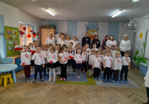 Dzieci i pracownicy przedszkola śpiewają hymn narodowy.