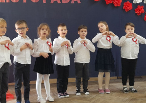 Grupka dzieci stoi obok siebie i śpiewa piosenkę "Hymn małego patrioty".
