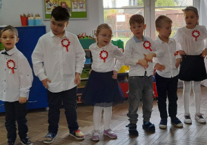 Sześcioro dzieci stoi obok siebie i śpiewa piosenkę "Hymn małego patrioty".