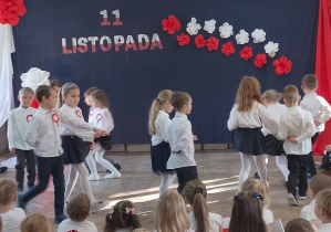 Dzieci w parach tańczą Poloneza po obwodzie koła. W tle dekoracja.