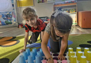 Olek i Maja układają kubeczki na macie do kodowania według kolorów.