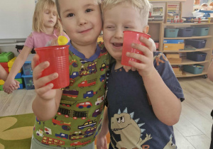 Szymek i Karol trzymają w dłoniach czerwone kubeczki.