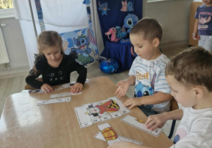 Zuzia, Szymek i Marcel układają bajkowe puzzle.