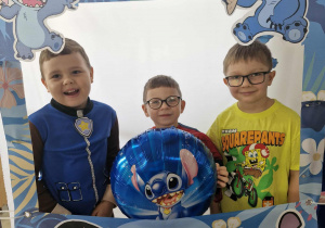 Oskar, Antoś i Tymuś pozują do zdjęcia przy foto - budce ze Stichem.