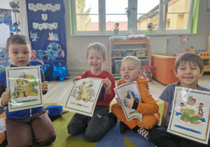 Oskar, Julek, Lucjan i Wojtuś trzymają w dłoniach obrazki z postaciami bajkowymi.