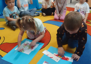 Dzieci w kole na dywanie, Maja i Michał układają bajkowe puzzle.