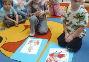 Laura i Szymon prezentują ułożone przez siebie bajkowe puzzle. Inne dzieci z grupy obserwują ich działania.