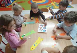 "Pszczółki" przy stolikach ozdabiają papierowymi elementami zakładkę do książki.