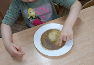 Podczas eksperymentu dziewczynki widać jak pieprz połączony z mydełkiem rozchodzi się na boki.