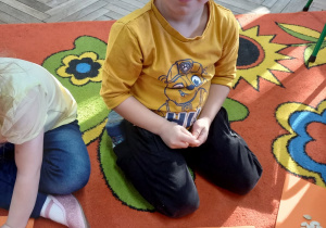 Chłopiec układa serduszko z pestek dyni.