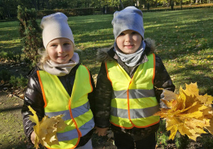 Ala i Szymek pokazują do zdjęcia swoje bukiety z liści zebranych w parku