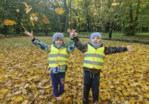 Olek i Szymek podskakują do góry rozrzucając wokół siebie kolorowe liście