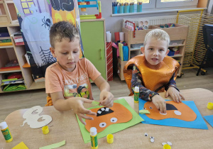 Franuś i Lucjan przy stoliku tworzą prace plastyczne